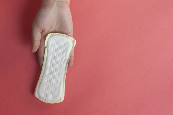 Woman's hands holding a feminine hygiene pad. Hands of female hold menstrual pads or sanitary napkins for women - Photo, Image