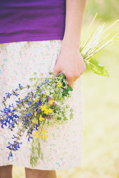 The girl is holding out a bouquet of wildflowers. - Fotó, kép