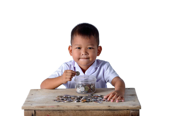 Симпатичный азиатский деревенский мальчик положить монеты в стеклянную чашу изолированы на
 - Фото, изображение