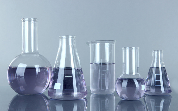 Test-tubes with light purple liquid on gray background - Fotoğraf, Görsel
