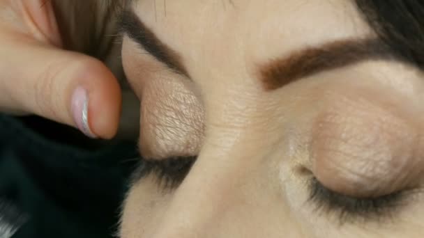 Professzionális smink művész elkezd ragaszkodni hamis szempillák a kék szeme egy felnőtt középkorú nő közelről kilátás - Felvétel, videó