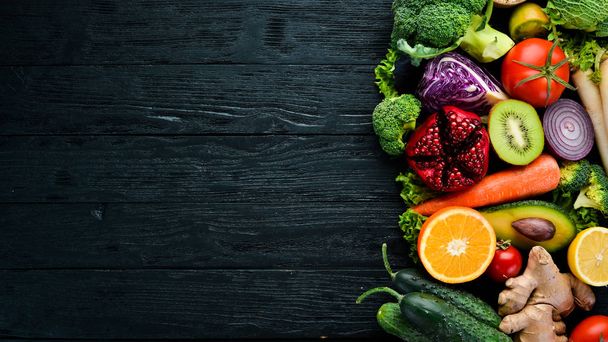 Fresh vegetables and fruits. Organic food on a black wooden background. Top view. Free copy space. - Фото, изображение