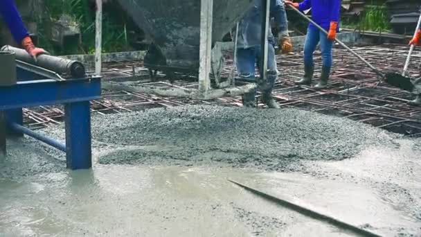 Homme utilisant une spatule en bois pour le ciment après avoir versé du béton prêt à l'emploi sur des armatures en acier pour rendre la route en mélangeant mobile le bétonnière
. - Séquence, vidéo