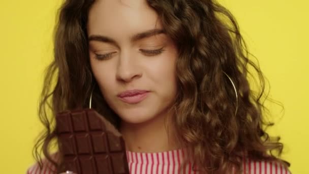 Šťastná žena si užívá čokoládovou tyčinku ve zpomaleném filmu. Model dívka s čokoládovou tyčinkou - Záběry, video