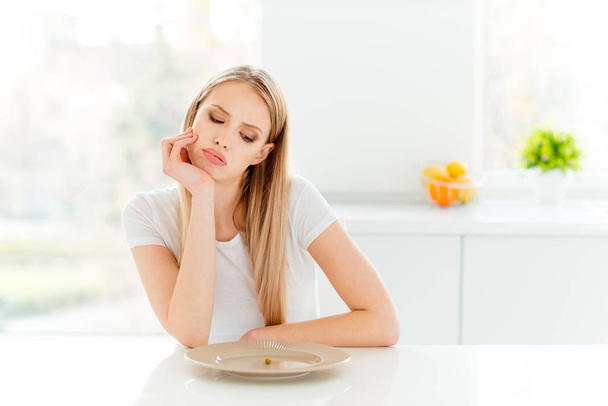 Portrait of irritated beautifiul teenager disappointed teen frustrated have lunch sit table touch chin tired unhealthy dressed trendy outfit in kitchen - Фото, зображення