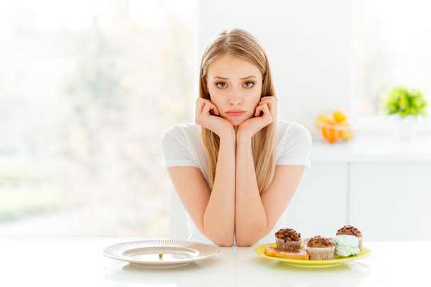 Portrait of disappointed youth hipster decide choose beautiful have problem empty dish hungry bakery confection sit table wear modern trendy outfit in big light  beautiful kitchen - Photo, image