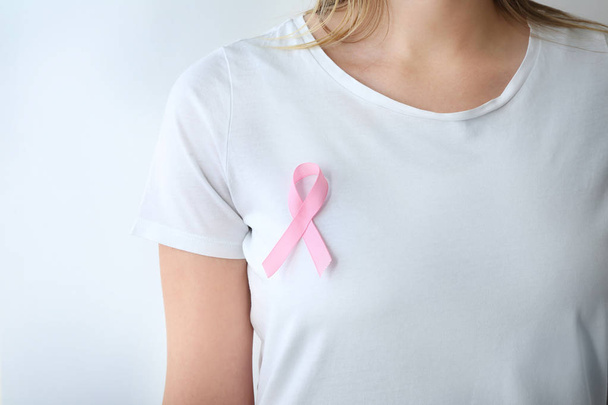Woman with pink ribbon on white background, closeup. Breast cancer awareness concept - Fotografie, Obrázek