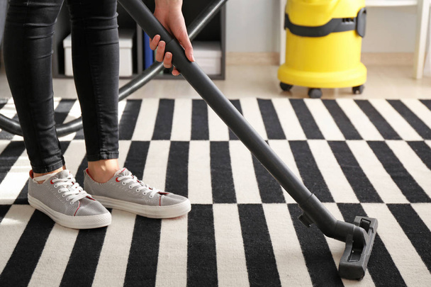 Woman hoovering carpet in flat - Photo, Image