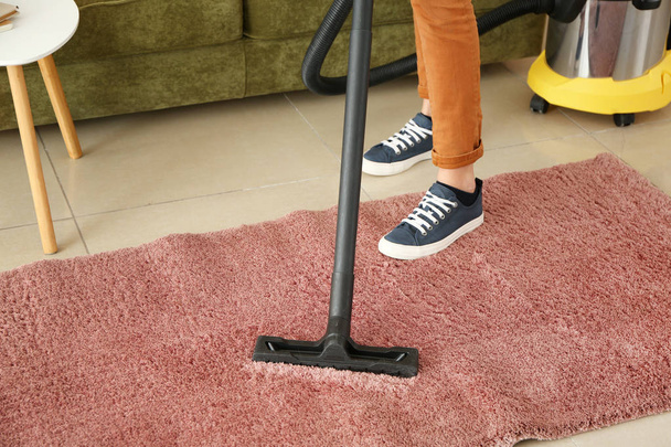 Frau putzt Teppich zu Hause mit Staubsauger - Foto, Bild