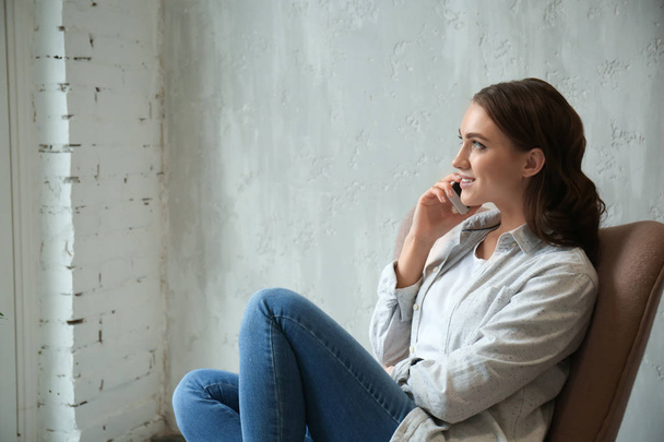 Όμορφη νεαρή γυναίκα μιλάει στο κινητό τηλέφωνο στο σπίτι - Φωτογραφία, εικόνα