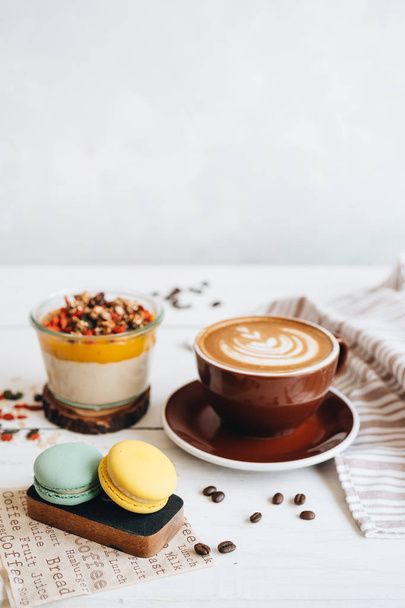 Delicious breakfast on the table. The cup of coffee, mango pudding and macarons at the white table. - Foto, imagen