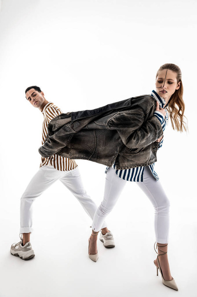 Male and female models wearing white trousers posing in one jacket - Фото, изображение