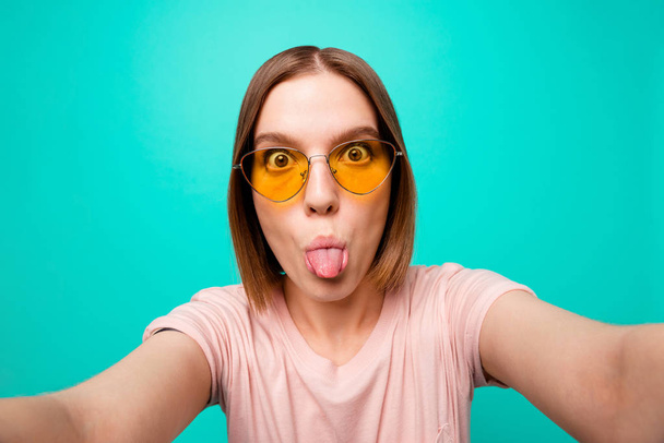 Close up photo beautiful her she lady modern look short straight hair make take selfies instagram post followers tongue out mouth careless wear specs casual t-shirt isolated teal turquoise background - Zdjęcie, obraz