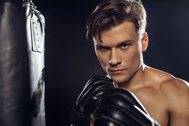 Boxer standing near punching bag and looking at camera - Фото, изображение