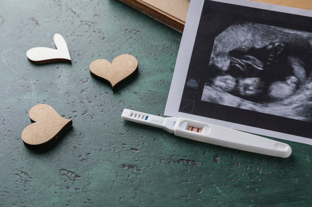 Sonograma de imagen y prueba de embarazo sobre fondo de color
 - Foto, Imagen