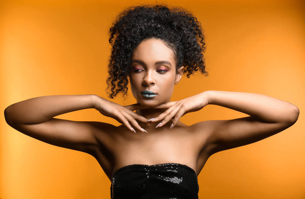 Portrait of beautiful African-American woman with unusual makeup on color background - Foto, Imagen