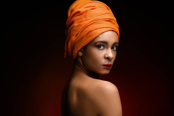Portrait of beautiful African-American woman with head scarf on dark color background - Foto, Imagem