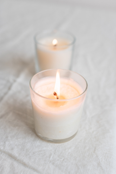 Burning candles in glasses on natural light fabric background - Photo, Image