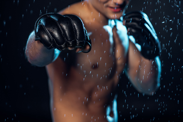Вибірковий фокус на боксері в шкіряних рукавичках, що стоять під краплями води на чорному
 - Фото, зображення