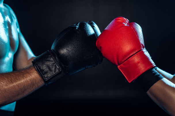 Partial view of two boxers in boxing gloves touching hands on black - Foto, immagini