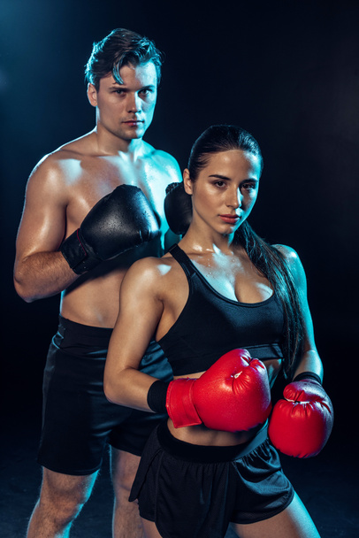 Two boxers in boxing gloves looking at camera on black - Foto, Imagem