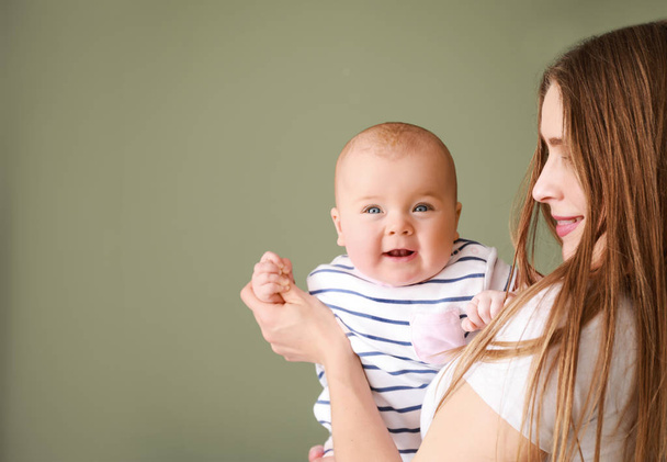 glückliche Mutter mit entzückendem Baby-Mädchen auf farbigem Hintergrund - Foto, Bild