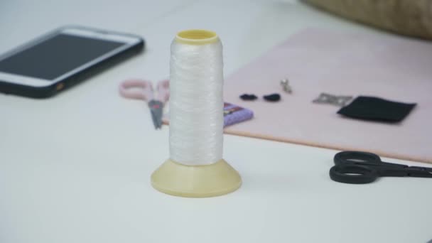 On the table for needlework is a spool of white thread and scissors are - Footage, Video