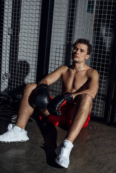 Boxer in white sneakers and black boxing gloves looking at camera - Photo, Image