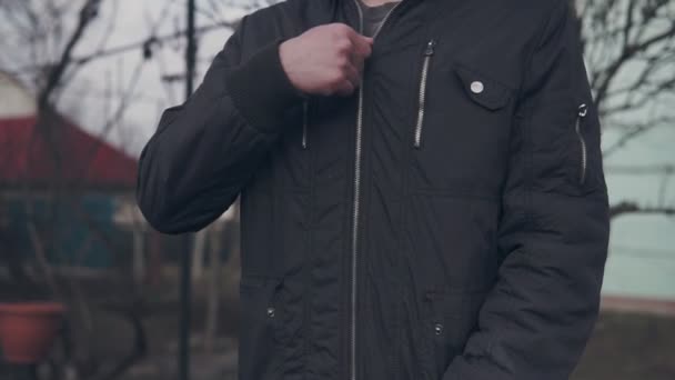 彼のジャケットのジッパーを登る若い男 - 映像、動画