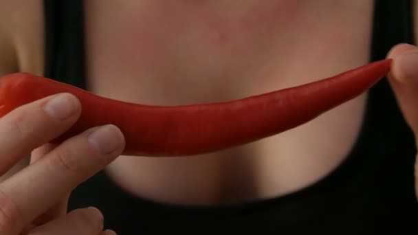 Γυναικεία χέρια αγγίζουν κόκκινες πιπεριές τσίλι σε μαύρο φόντο - Πλάνα, βίντεο
