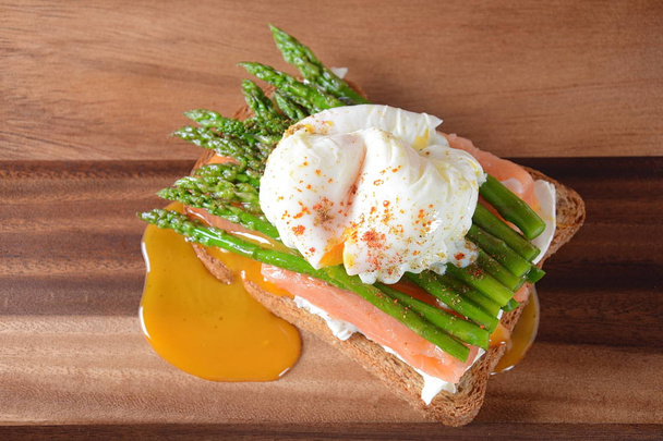 Poached egg with fried asparagus, cream cheese, salmon and spices on a toast. Poached egg with leak.Healthy French breakfast concept - Foto, Imagem