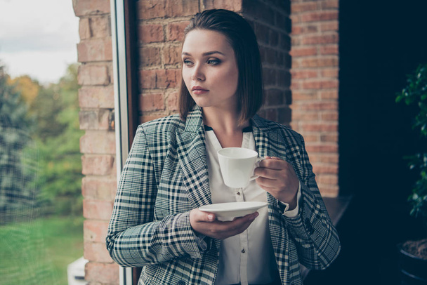 Close up photo amazing busy she her business lady concentrated look through window dreamer hold arms hands white glass mug beverage sit window sill office wear specs formal-wear checkered plaid suit - Foto, Imagen