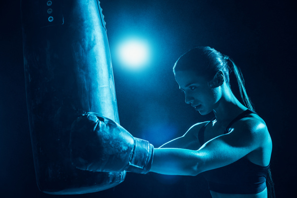 Уверенная женщина-боксер с тренировками на хвосте и боксерской грушей
 - Фото, изображение