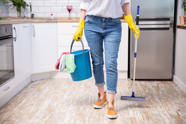 Mujer joven con fregona y detergentes en cocina, primer plano. Servicio de limpieza
 - Foto, imagen