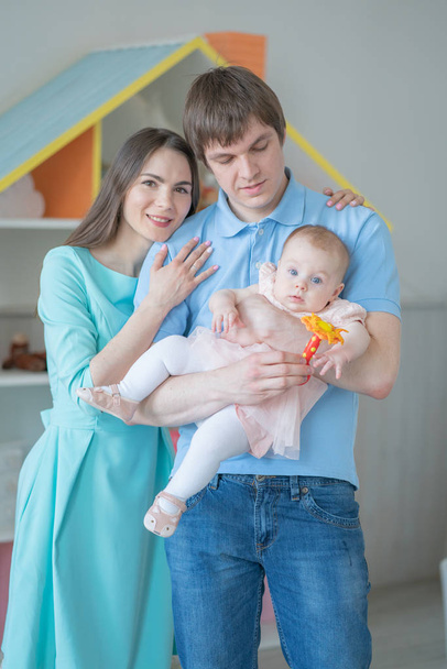 schöne enge Familie aus Mutter, Vater und Tochter posiert in ihrem weißen Zimmer - Foto, Bild