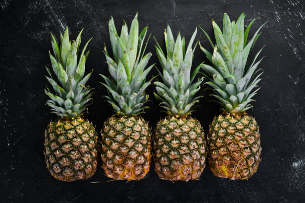 Fresh pineapple on a black stone background. Top view. Free copy space. - Foto, immagini