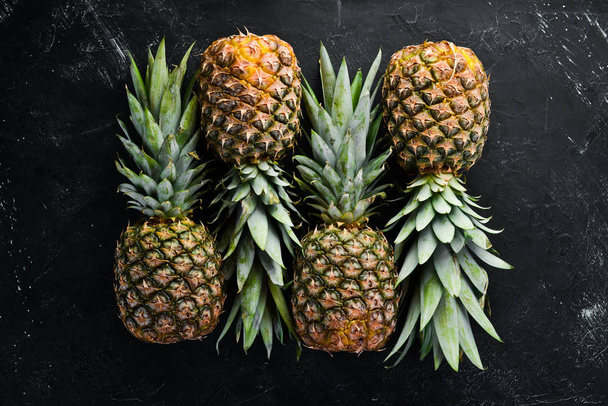 Fresh pineapple on a black stone background. Top view. Free copy space. - Foto, afbeelding