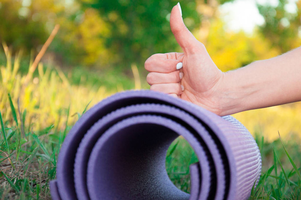 Bokeh arka plana karşı parmak ile açık havada Dambıl ile yoga mat - Fotoğraf, Görsel