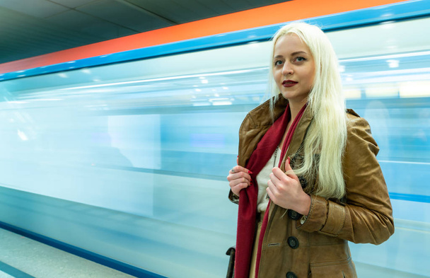 Beautiful young girl in the subway on a blurred background in train traffic - Zdjęcie, obraz