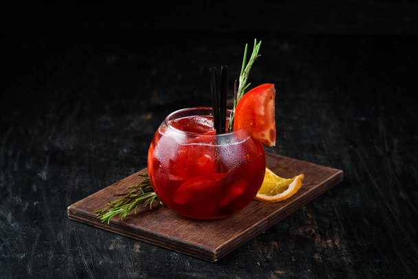 Tomato cocktail. Gin, cranberry juice, tomatoes, ice. On a wooden background. Top view. - Foto, afbeelding