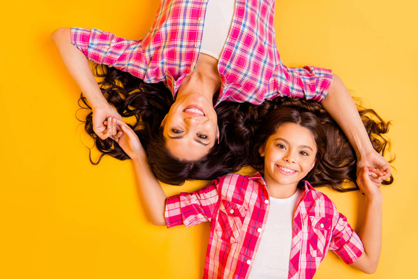 Close up top above high angle view photo beautiful she her models mom daughter caress arms together long hair weekend lying floor wear casual pink plaid checkered shirts isolated yellow background - Foto, afbeelding