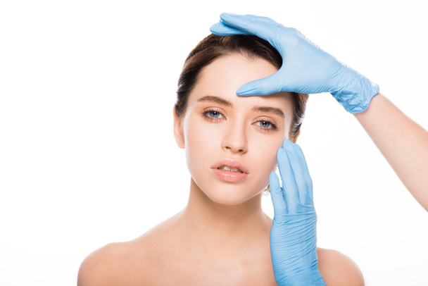 vista ritagliata del chirurgo plastico in guanti di lattice volto toccante di donna attraente isolato su bianco
 - Foto, immagini