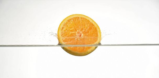 slice orange dropping into water isolated white background - Foto, Imagem