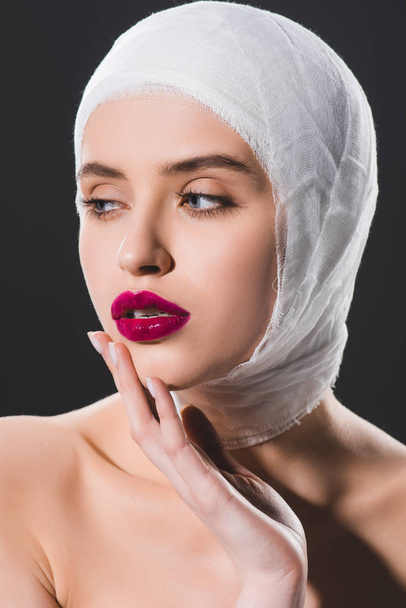 attractive girl with bandaged head touching face isolated on grey  - Foto, Imagem