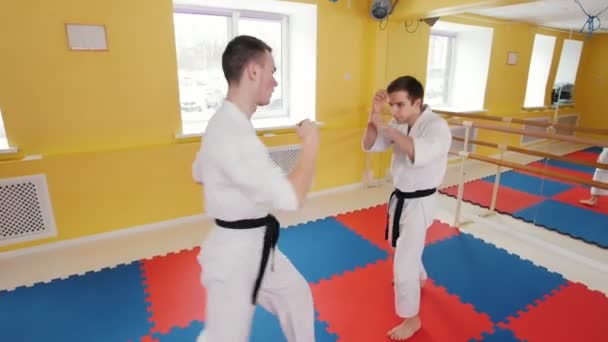 Artes marciales. Dos hombres entrenando sus habilidades de aikido en el estudio. Protegiendo de un golpe en la pierna y tirando al oponente al suelo
 - Metraje, vídeo