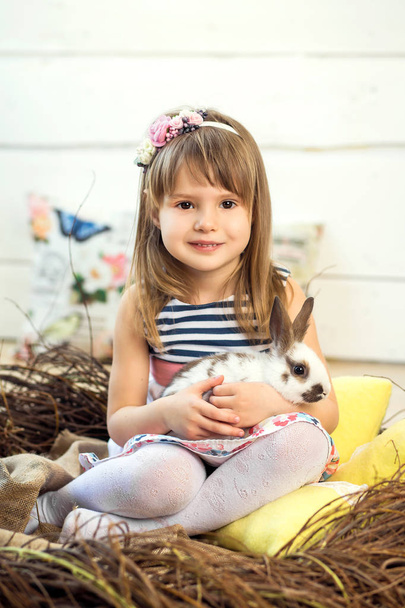 A happy little girl in a dress sits in a nest and holds a cute f - Fotó, kép