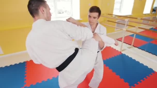 武道。2人のアスレチック男性が彼らの合気道のスキルを訓練します。足からの保護がヒットし、床に相手を投げます - 映像、動画