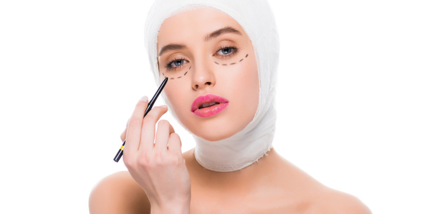 panoramic shot of young woman with marks on face and bandaged head holding marker pen isolated on white  - Fotografie, Obrázek