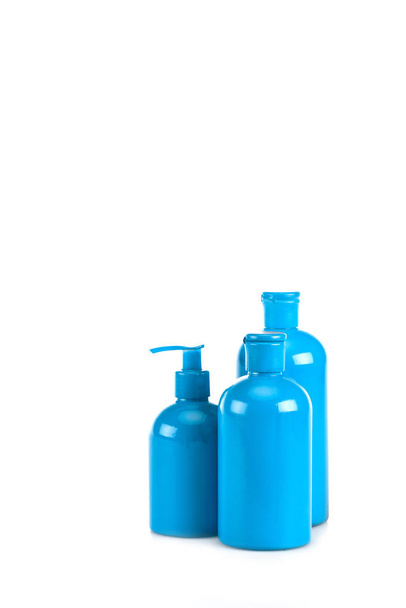 Blue cosmetic bottles with spray and caps on white - Zdjęcie, obraz