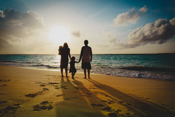 Szczęśliwa rodzina z dzieckiem grać na zachód słońca plaża - Zdjęcie, obraz
